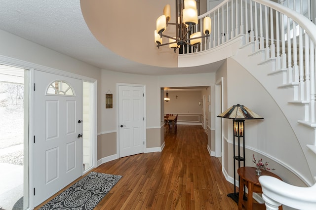 foyer entrance featuring stairs, baseboards, wood finished floors, and a chandelier