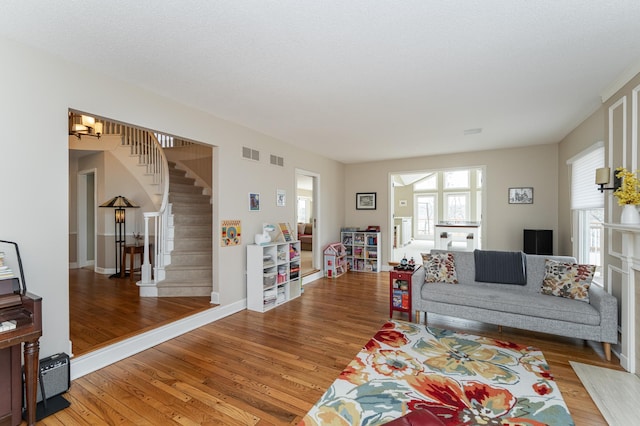 living area featuring visible vents, light wood-style flooring, baseboards, and stairs