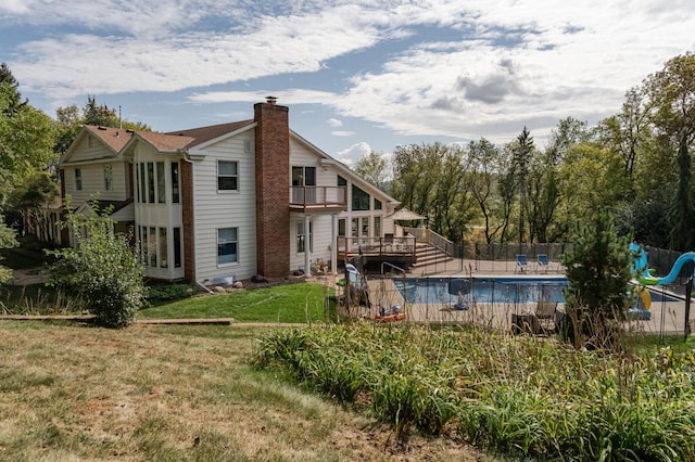 view of swimming pool featuring a fenced in pool, a water slide, fence, and a lawn