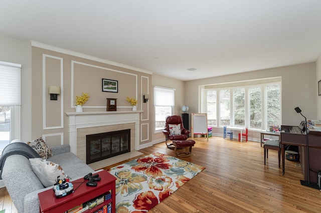 living area with a fireplace with flush hearth, wood finished floors, and baseboards