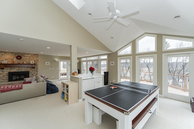 game room with high vaulted ceiling, recessed lighting, light carpet, and a stone fireplace