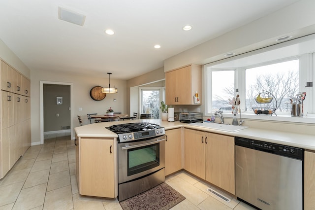 kitchen featuring appliances with stainless steel finishes, light brown cabinets, a sink, and visible vents