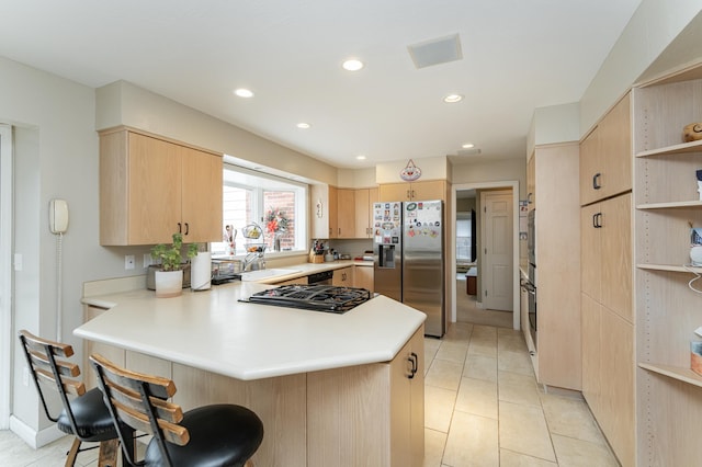 kitchen with light brown cabinetry, a peninsula, stainless steel fridge, and light countertops