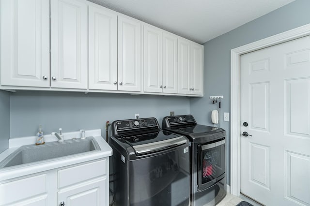 clothes washing area featuring washing machine and dryer, cabinet space, and a sink