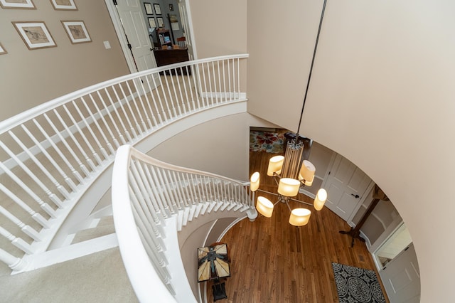 stairway featuring arched walkways, a high ceiling, wood finished floors, and a chandelier