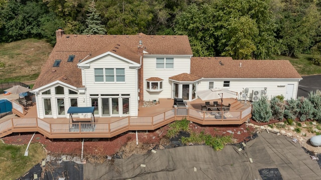 back of property with roof with shingles and a wooden deck