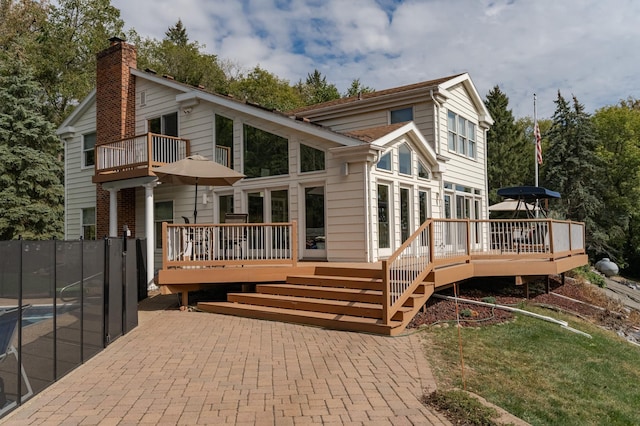 back of property featuring a patio, a balcony, a chimney, fence, and a wooden deck