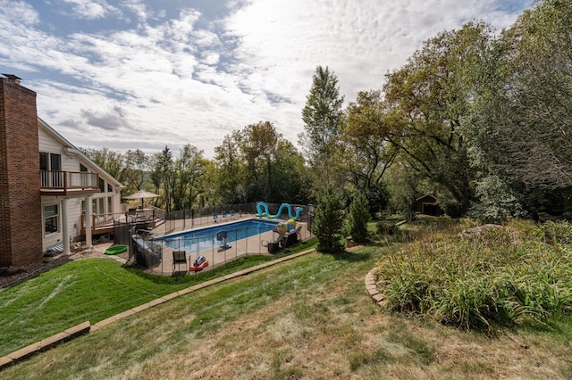 view of pool with a fenced in pool, a yard, fence, a water slide, and a wooden deck