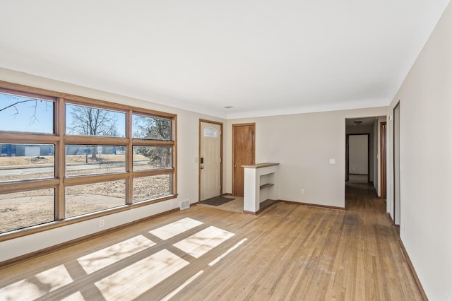 unfurnished room featuring light wood-style flooring, visible vents, and baseboards