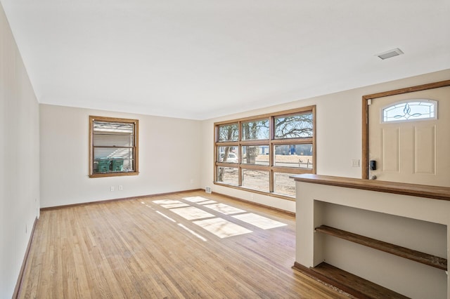 interior space featuring light wood-type flooring, visible vents, and baseboards