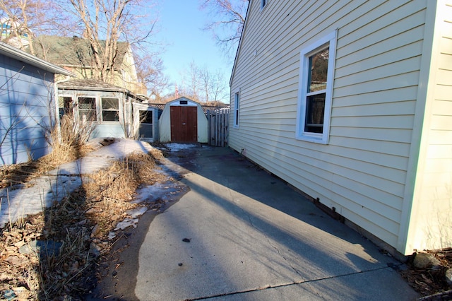 view of side of property featuring fence, a storage unit, and an outdoor structure