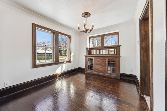 unfurnished living room with ornamental molding, hardwood / wood-style floors, and a notable chandelier