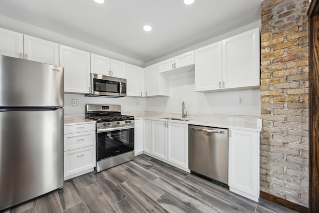 kitchen with appliances with stainless steel finishes, white cabinets, light countertops, and a sink