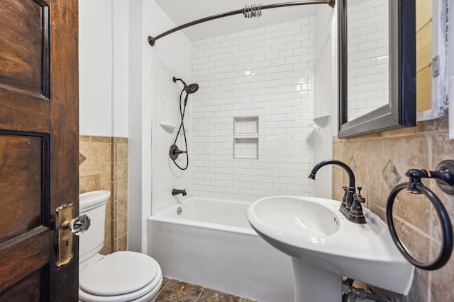 bathroom with toilet, a sink, tile walls, and shower / bathtub combination