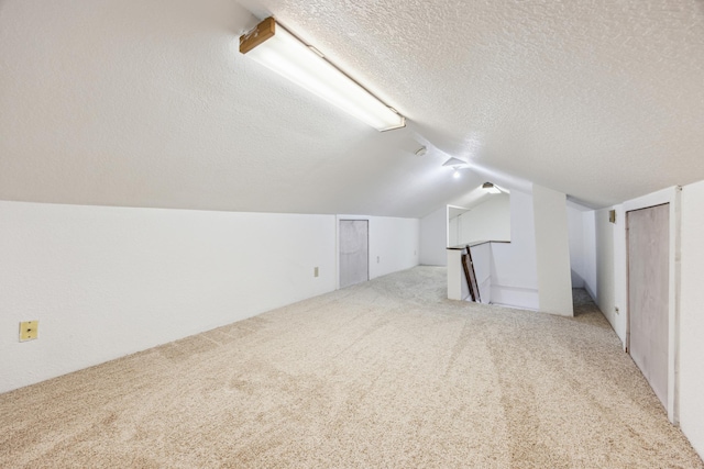 bonus room featuring carpet flooring, vaulted ceiling, and a textured ceiling