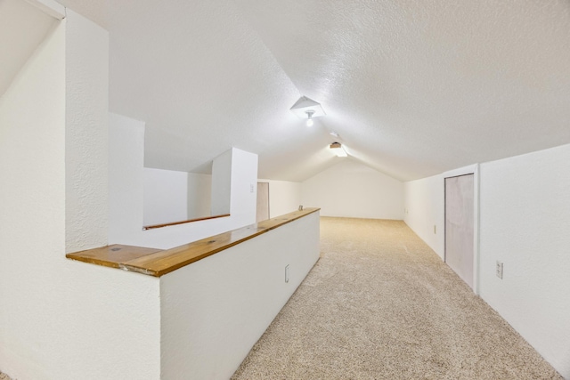 additional living space with lofted ceiling, carpet flooring, and a textured ceiling