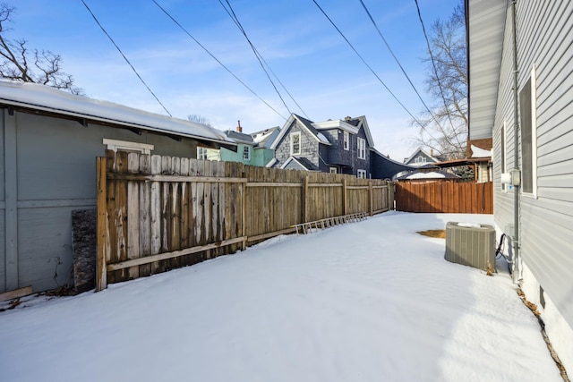 yard layered in snow with central AC unit and fence