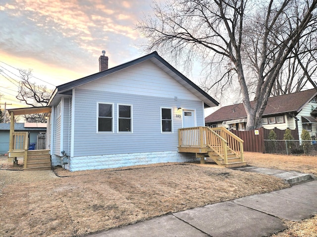 view of front facade featuring a chimney and fence