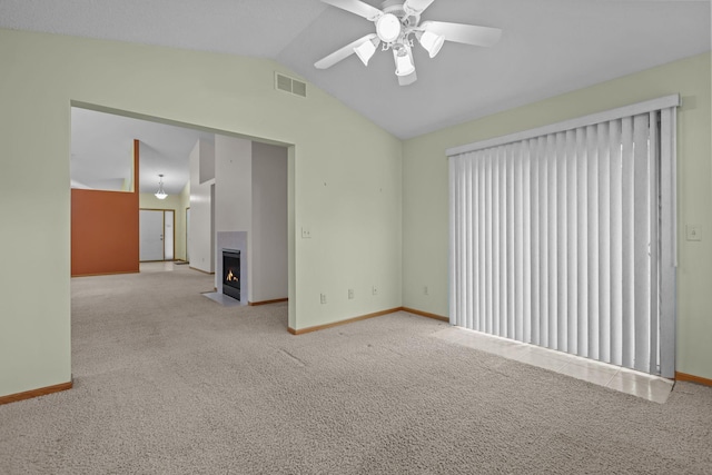 spare room featuring visible vents, baseboards, lofted ceiling, a fireplace with flush hearth, and carpet