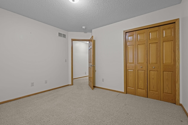 unfurnished bedroom featuring baseboards, a textured ceiling, visible vents, and carpet flooring