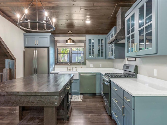 kitchen with stainless steel appliances, dark wood-style flooring, a sink, wall chimney exhaust hood, and glass insert cabinets