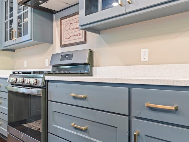 kitchen with stainless steel gas range, gray cabinetry, and extractor fan