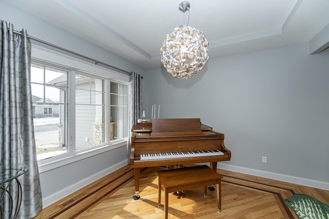 living area featuring a tray ceiling, baseboards, and a healthy amount of sunlight