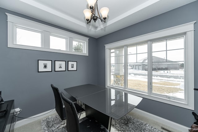 office area featuring a chandelier, a tray ceiling, baseboards, and carpet floors