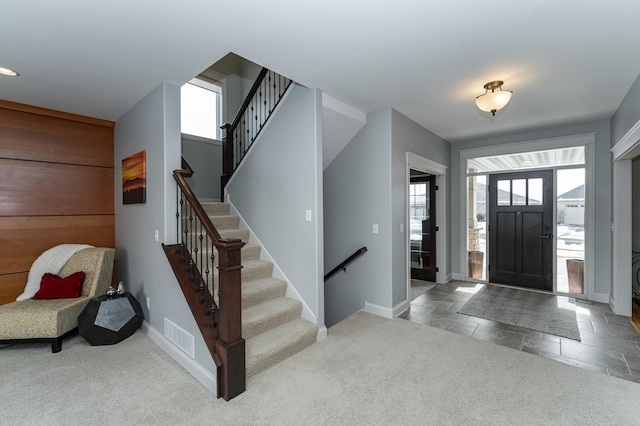 entrance foyer featuring visible vents, baseboards, carpet, and stone tile floors