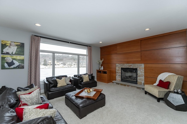 carpeted living area featuring wooden walls, recessed lighting, and a fireplace