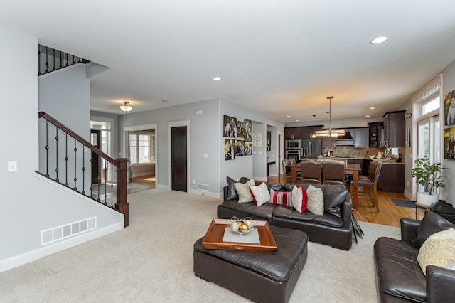 living area featuring visible vents, recessed lighting, stairs, and baseboards