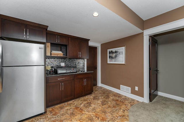 kitchen featuring visible vents, baseboards, tasteful backsplash, and freestanding refrigerator