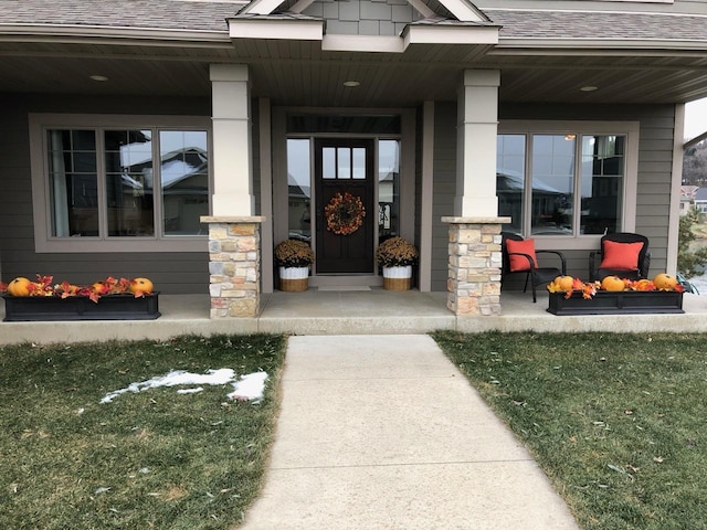 view of exterior entry featuring stone siding, a porch, and a shingled roof