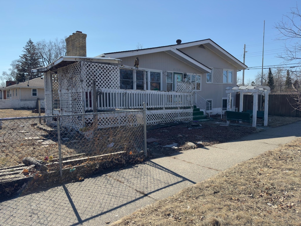 rear view of house with fence, a chimney, a wooden deck, and a pergola