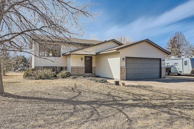 split level home featuring driveway, brick siding, and an attached garage