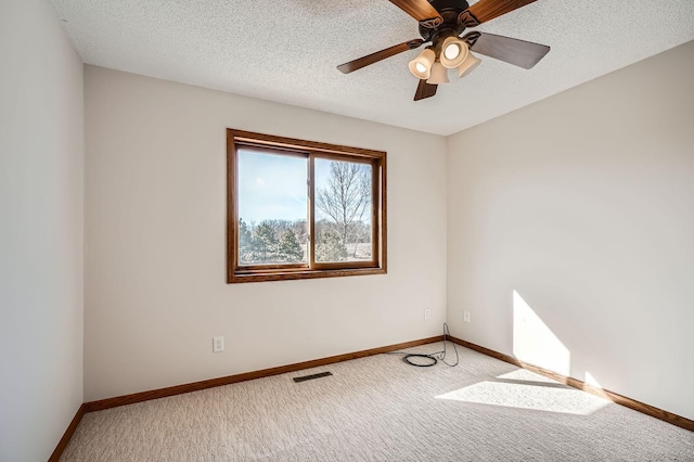 empty room with a textured ceiling, visible vents, baseboards, and light carpet