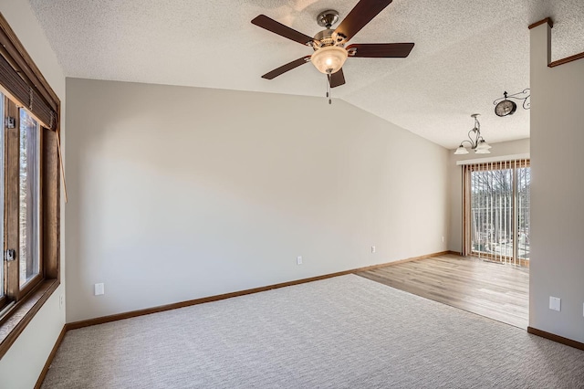 carpeted spare room featuring baseboards, a textured ceiling, and vaulted ceiling