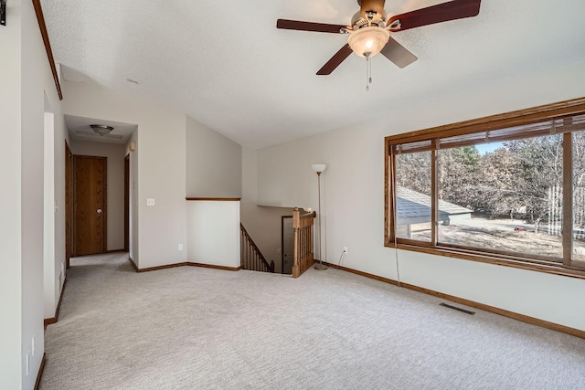 carpeted spare room featuring visible vents, lofted ceiling, a textured ceiling, and baseboards