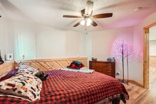 bedroom with ceiling fan, a textured ceiling, and wood finished floors