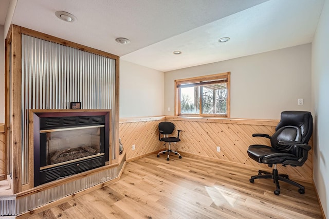 office with a wainscoted wall, a glass covered fireplace, wood finished floors, recessed lighting, and wooden walls