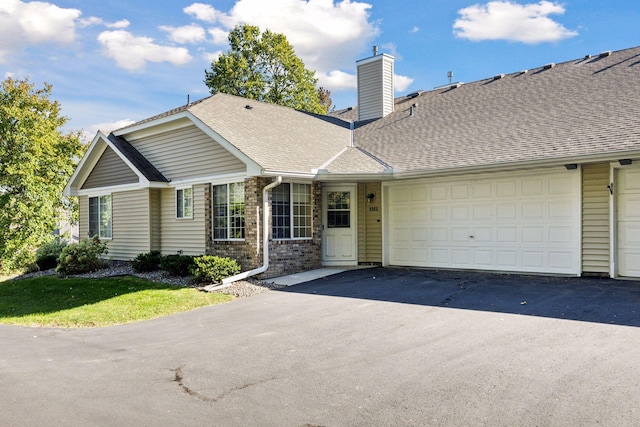 ranch-style house featuring aphalt driveway, an attached garage, a chimney, and a shingled roof