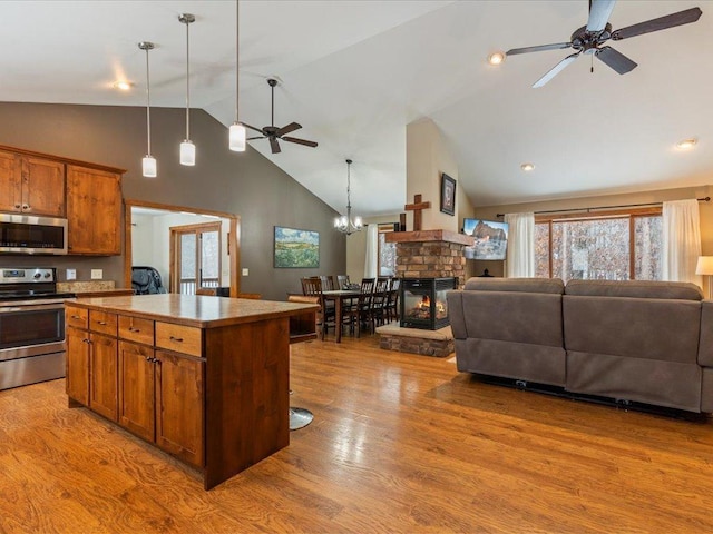 kitchen with a kitchen island, open floor plan, ceiling fan with notable chandelier, appliances with stainless steel finishes, and wood finished floors