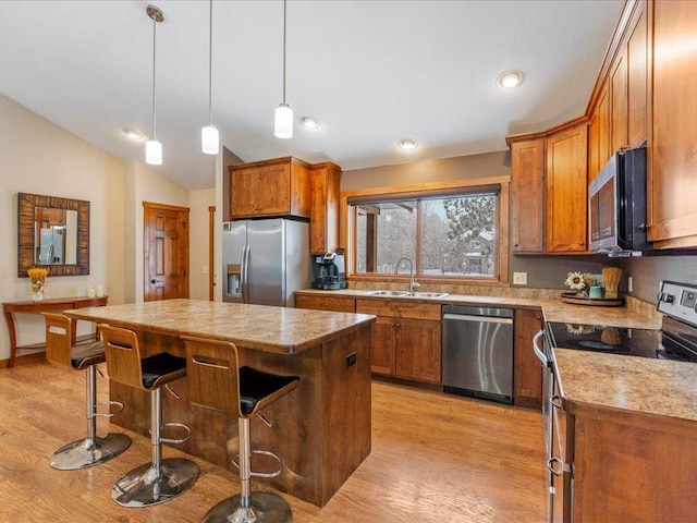 kitchen featuring light wood finished floors, vaulted ceiling, brown cabinetry, stainless steel appliances, and a sink