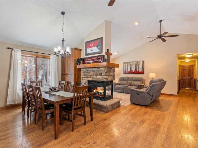 dining room with light wood-style flooring, a fireplace, baseboards, and a ceiling fan