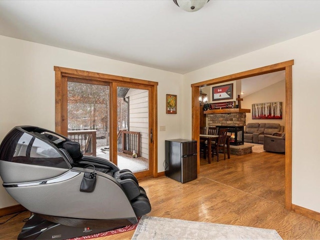 living area with wood finished floors, a fireplace, baseboards, and lofted ceiling