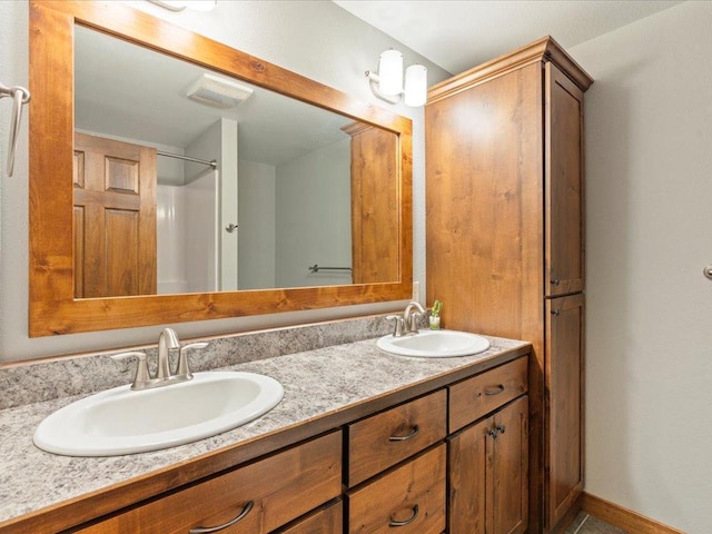 bathroom featuring double vanity, visible vents, baseboards, and a sink