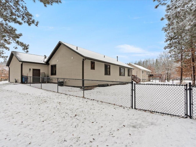 snow covered rear of property featuring central AC and fence private yard