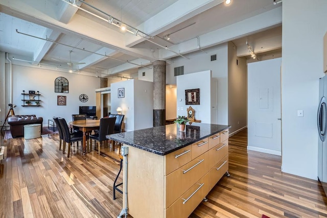 kitchen featuring a breakfast bar area, a kitchen island, visible vents, light wood finished floors, and rail lighting