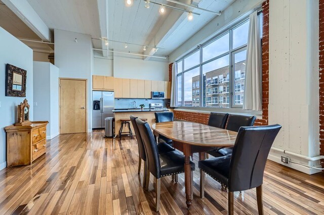 dining room with track lighting, light wood-type flooring, and a high ceiling