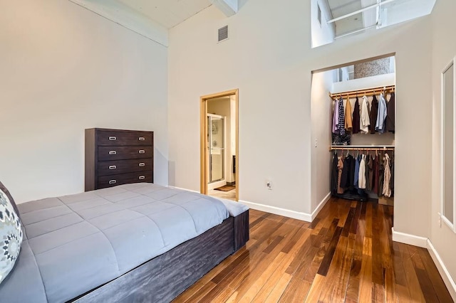 bedroom with visible vents, baseboards, a closet, hardwood / wood-style floors, and a walk in closet